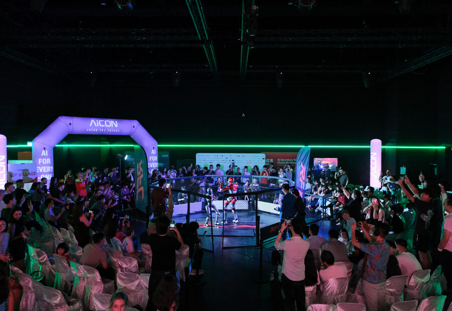 A packed hall of spectators filming around the RFC cage during a live bout